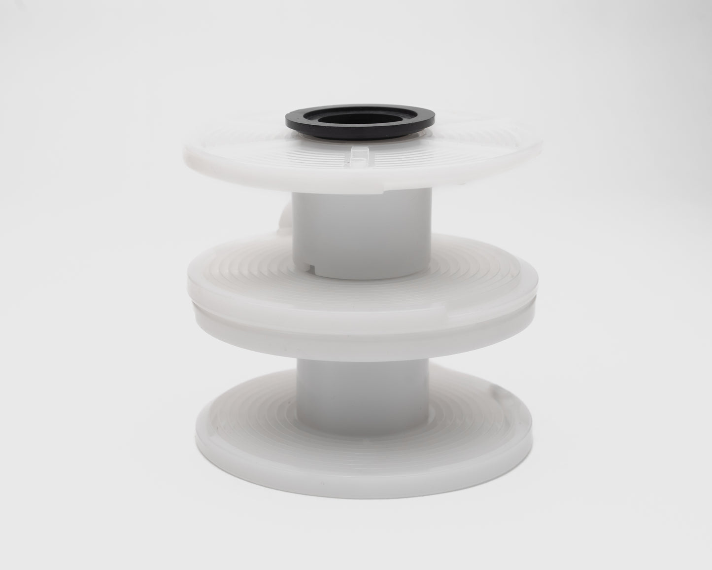 White plastic spool with black top on a white background