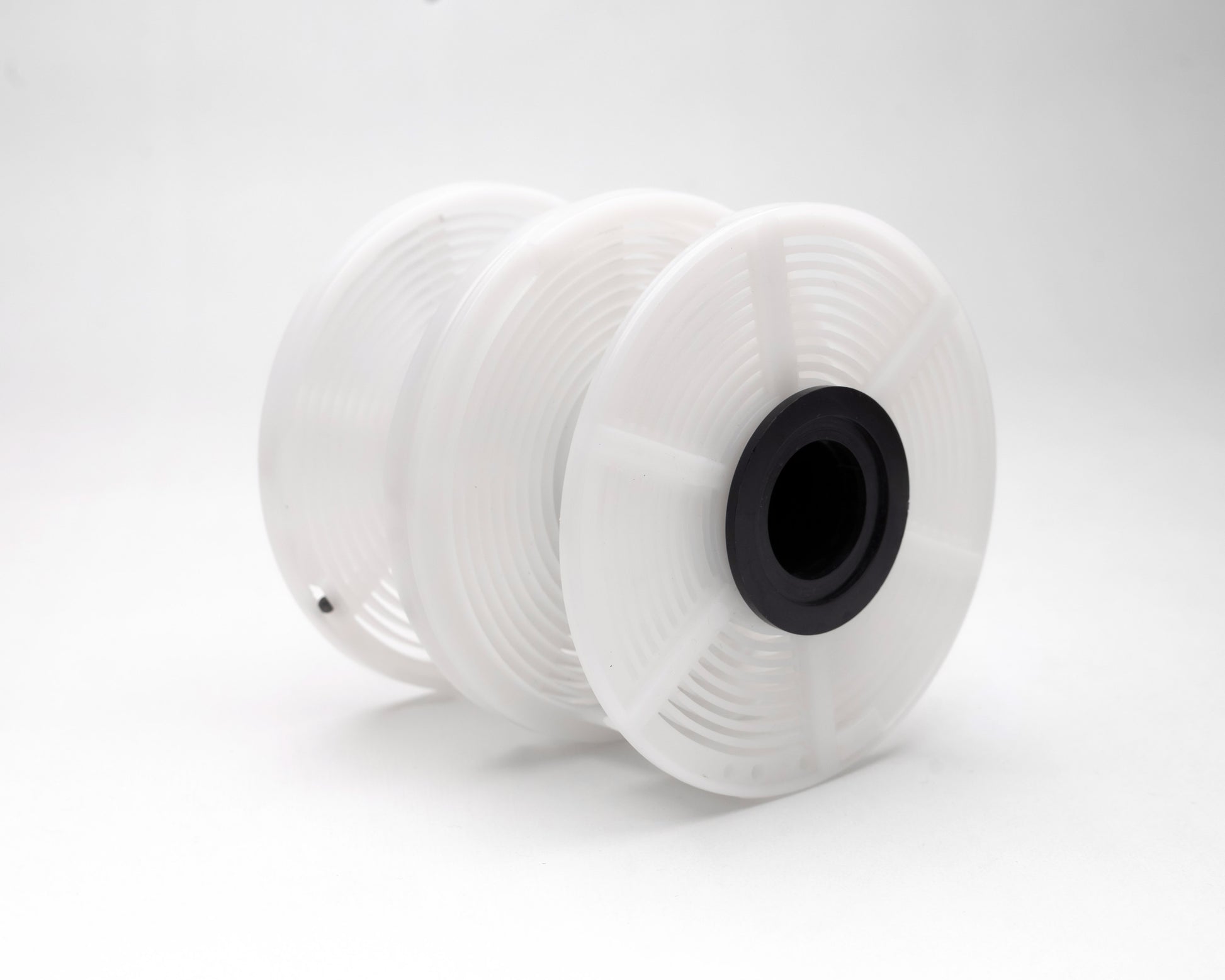 white film developing reels stacked together with black center on a white background